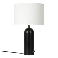 Black cylindrical lamp base with a white round shade and gold accent. Modern, minimalist design for versatile decor.