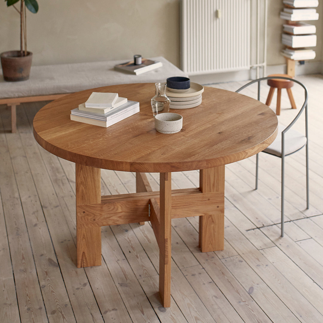 Round wooden dining table with a natural oak finish, featuring a simple design and smooth surface.
