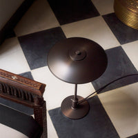 "Modern brown lamp on black and white checkered floor, highlighting sleek design and elegant curves."