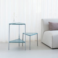 Aqua blue geometric side tables with a sleek chrome frame against a soft, neutral backdrop.