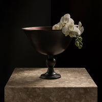 Elegant bronze bowl with a smooth finish, featuring delicate white orchids for a touch of nature.