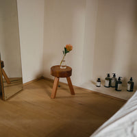 Wooden stool in warm brown with a light beige backdrop; simple, modern design enhances any space.