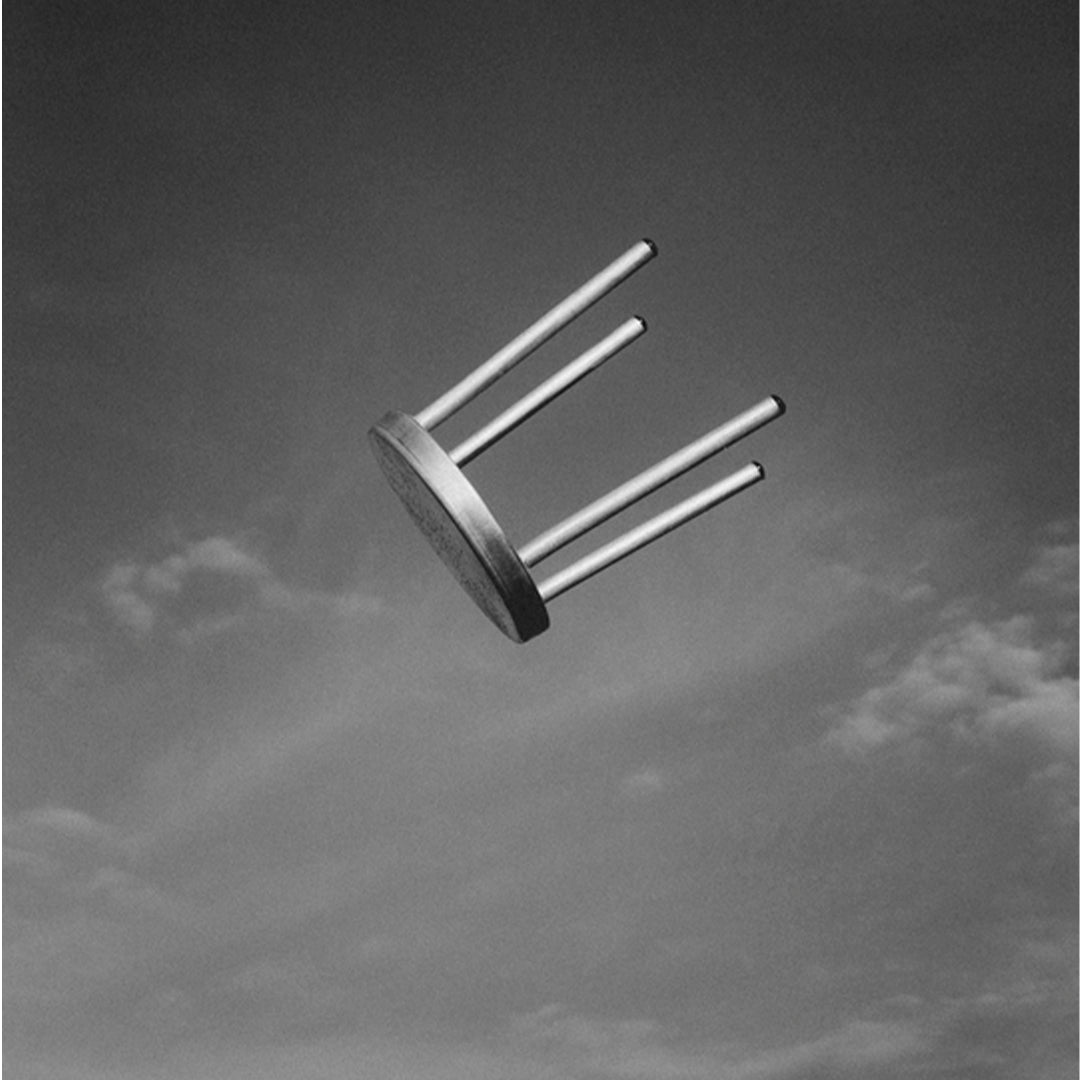Black and white image of a minimalist chair, featuring a smooth, circular seat and sleek metal legs.