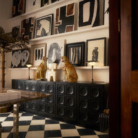 Black and white checkered floor with black cabinetry and abstract wall art featuring bold patterns and earthy tones.