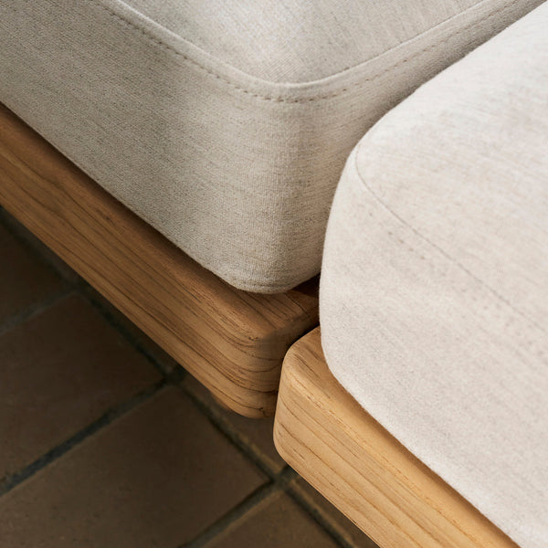 Close-up of light beige sofa cushions with a smooth texture, paired with natural wood base. Modern and minimalist design.