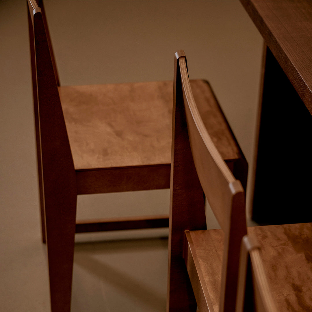 "Warm wood-toned chairs with a smooth finish, featuring a minimalist design against a soft, neutral background."