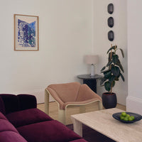 "Soft beige chair with a minimalist design, paired with a rich burgundy sofa and neutral-toned decor."