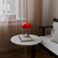 "Vibrant red dome lamp on a sleek white table, featuring neutral tones in a minimalistic room setting."