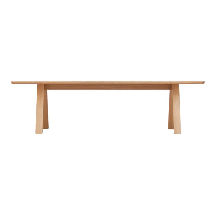 Natural wood dining table with a sleek finish and minimalist design, featuring light beige tones and clean lines.
