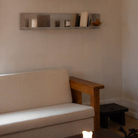 Neutral beige sofa with wooden armrest, complemented by a minimalist metallic shelf and subtle decor accents.