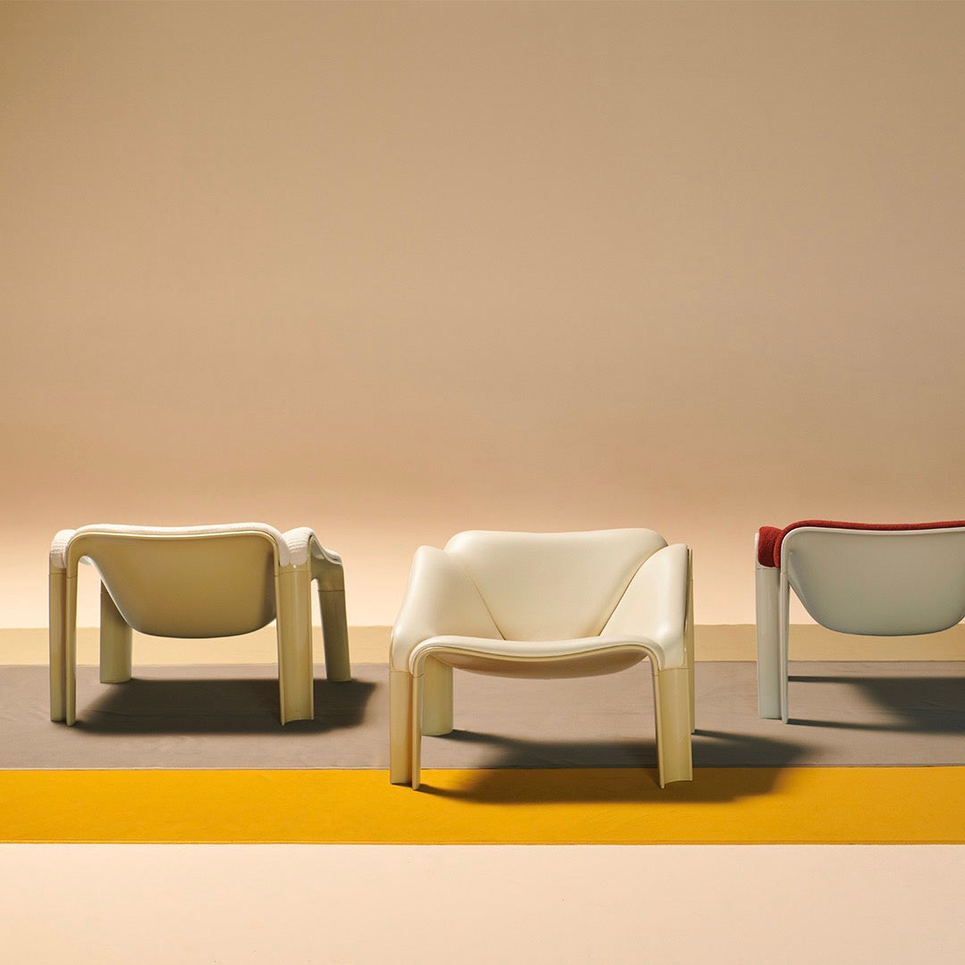 Set of three modern chairs in cream, red, and gray against a warm pastel background with bold geometric patterns.