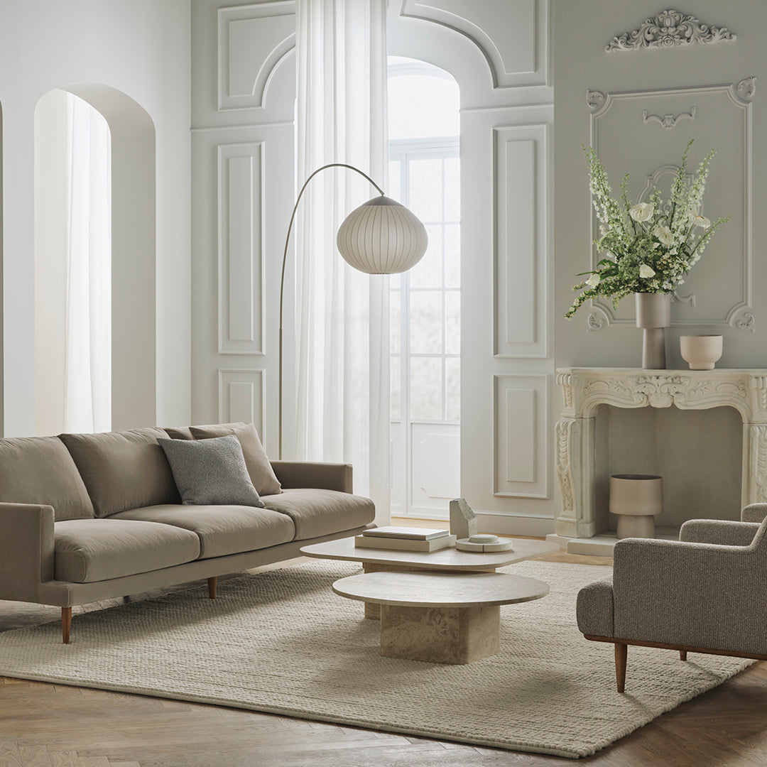 Modern living room with neutral beige and gray tones, featuring soft textures and subtle patterns on furniture and rug.