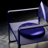 Vibrant purple chair with a round, plush cushion and sleek geometric design against a dark backdrop.