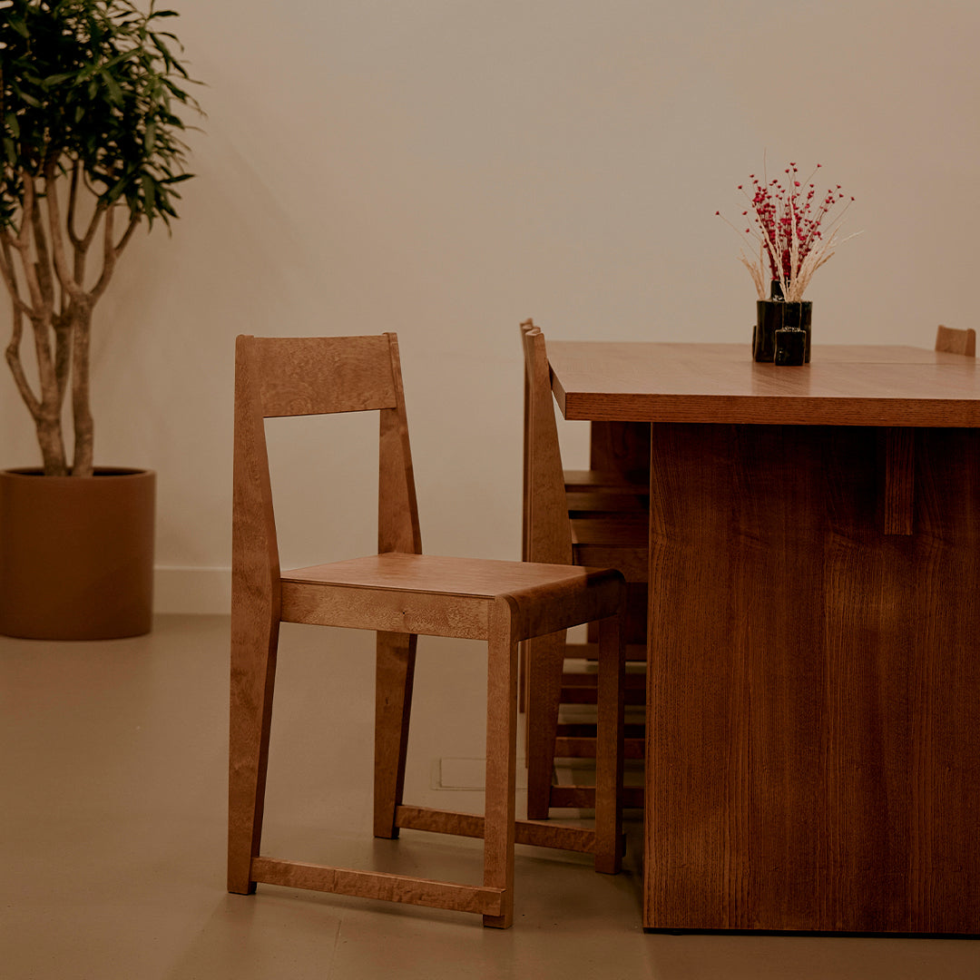 Wooden dining chair in warm brown tones with a minimalist design, paired with a matching table setting.