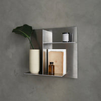 Modern silver shelf with sleek lines, featuring a neutral beige vase, black and white decor items, against a gray background.
