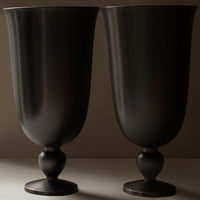 Pair of matte black vases with smooth, curved designs and round pedestals, perfect for modern decor.