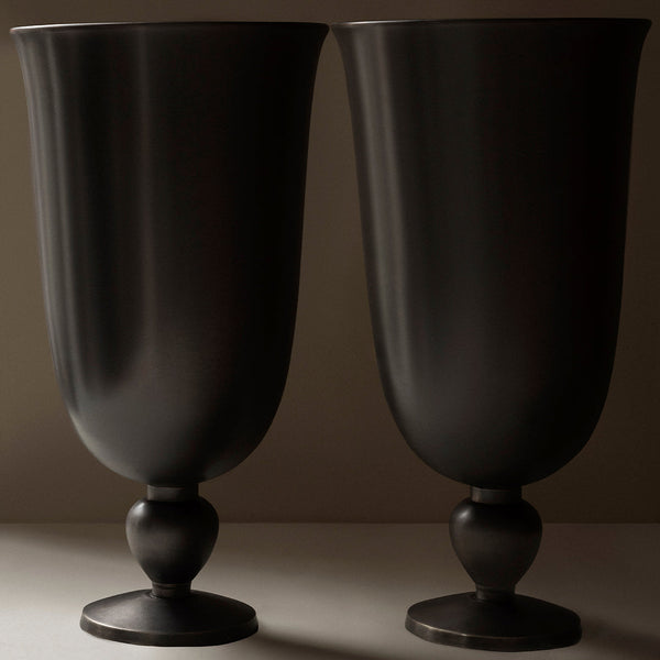 Pair of matte black vases with smooth, curved designs and round pedestals, perfect for modern decor.