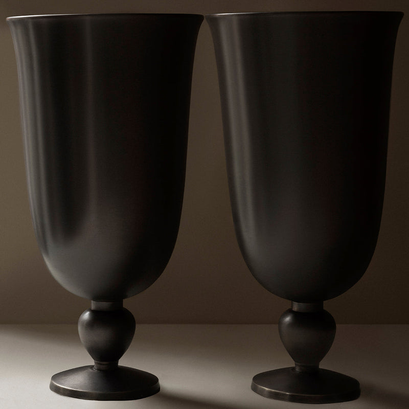 Pair of matte black vases with smooth, curved designs and round pedestals, perfect for modern decor.