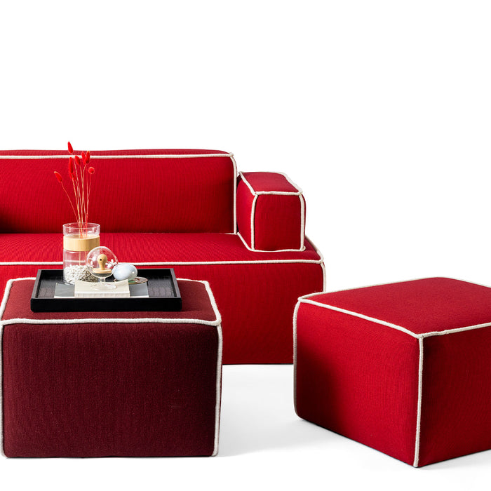Red sofa with cream trim and matching red and burgundy ottomans, showcasing vibrant colors and textures.