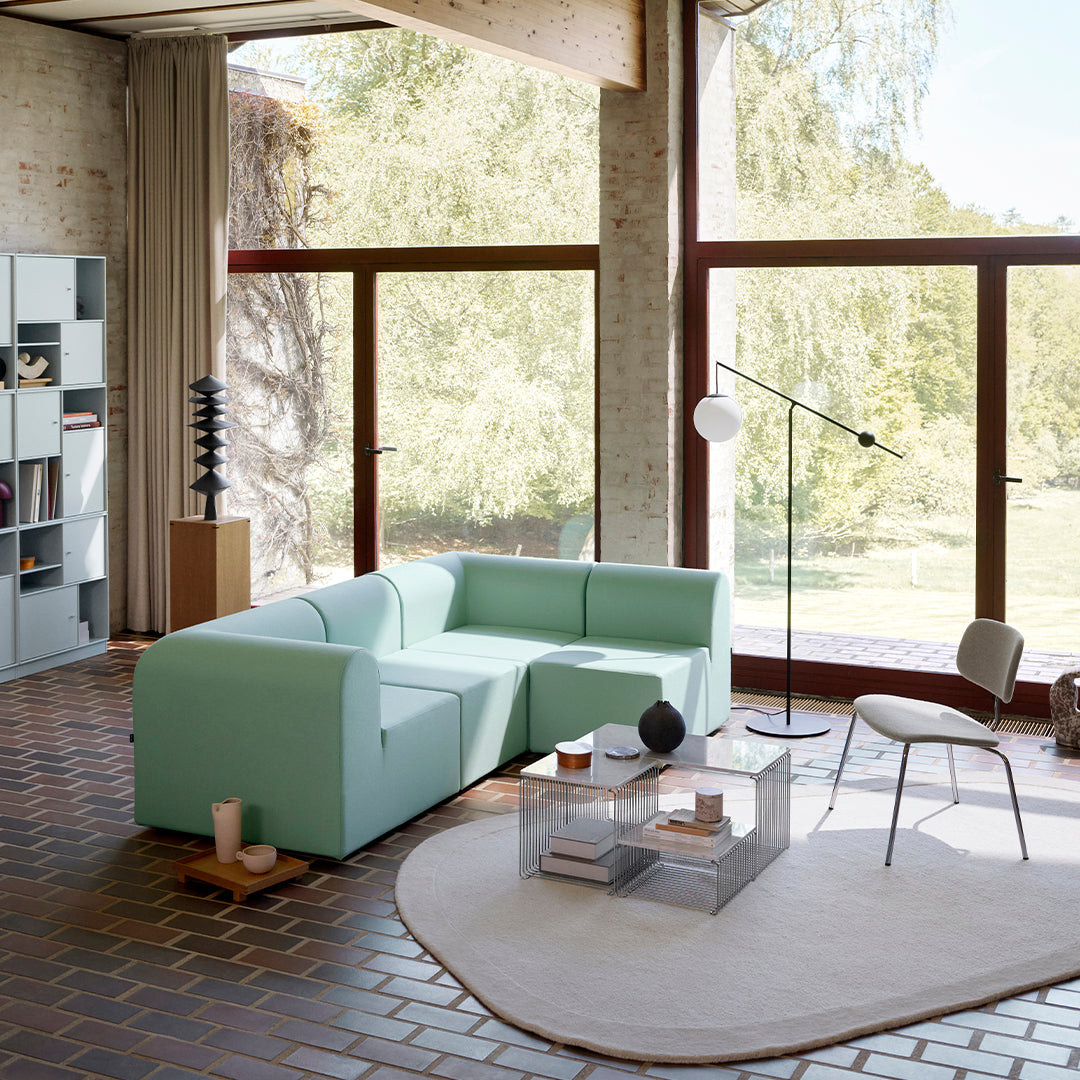 Mint green sectional sofa, soft beige rug, and gray accents create a modern, fresh living space. Stylish patterns and textures.