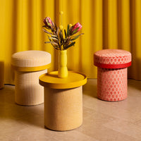 Colorful dining stools in yellow, pink, and cream patterns against a vibrant yellow backdrop.