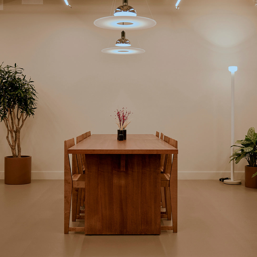 "Elegant wooden dining table with a rich brown finish, set against a neutral background and lush green plants."