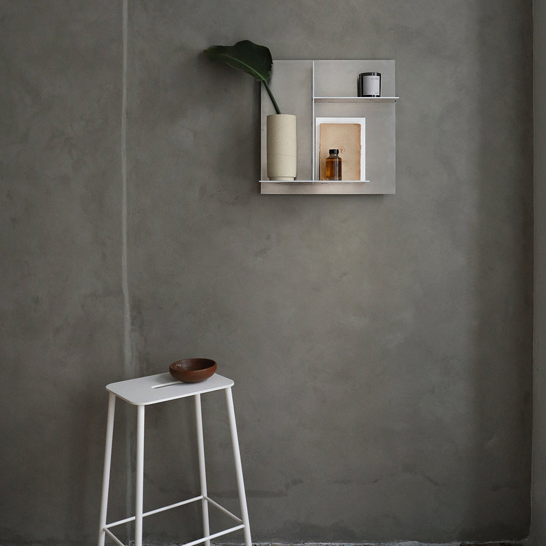 Modern gray wall with minimalist beige and white shelf, featuring green plant and decorative items. Sleek, contemporary style.