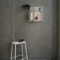 Modern gray wall with minimalist beige and white shelf, featuring green plant and decorative items. Sleek, contemporary style.