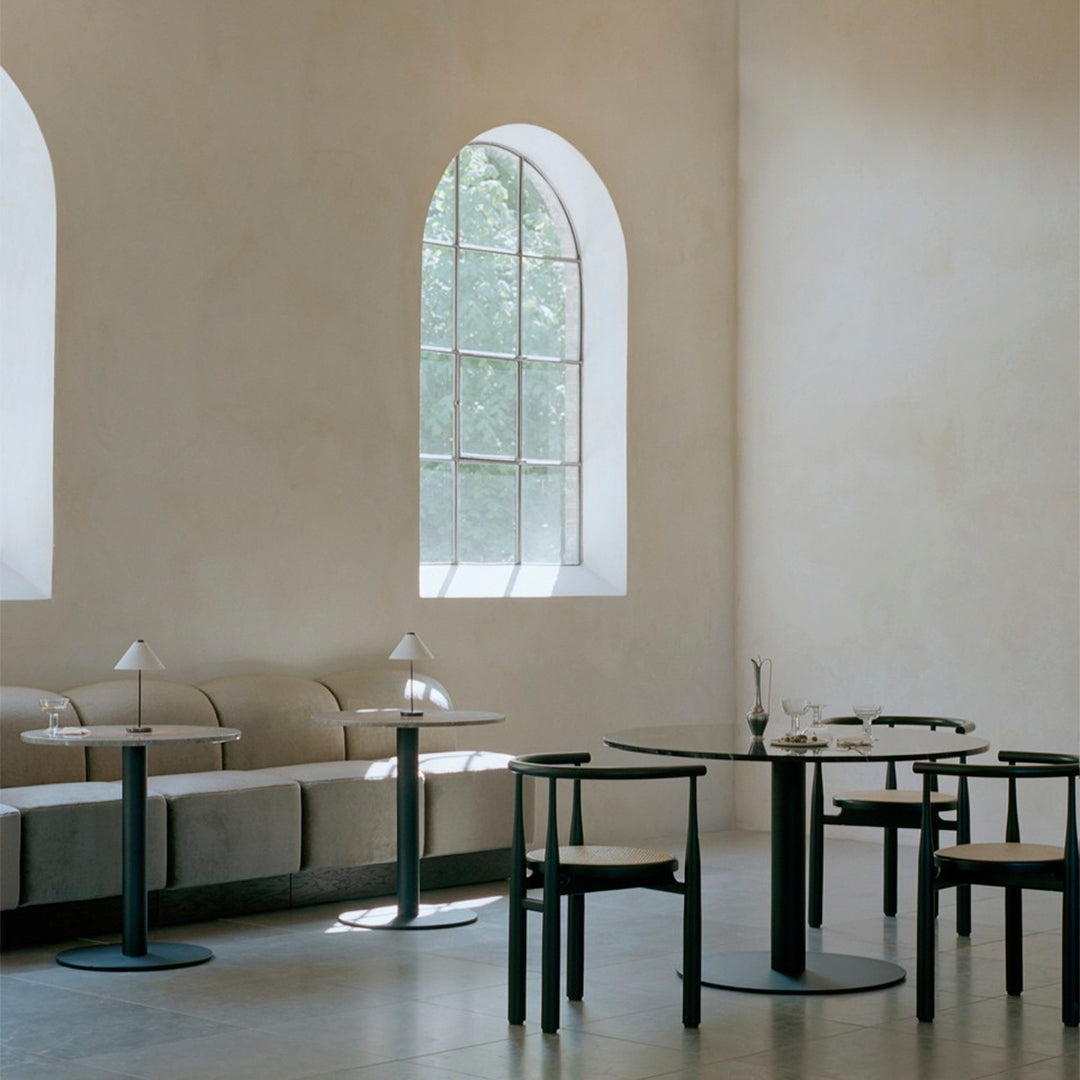 Modern minimalist dining space featuring black furniture and neutral-toned walls, complemented by natural light.