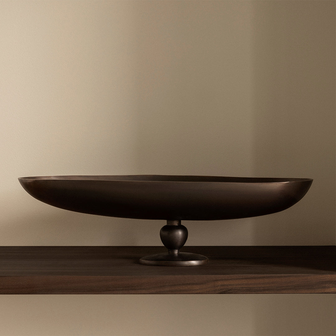 Elegant dark bronze oval platter on a sleek wooden shelf, highlighting a smooth metallic finish.