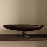 Elegant dark bronze oval platter on a sleek wooden shelf, highlighting a smooth metallic finish.