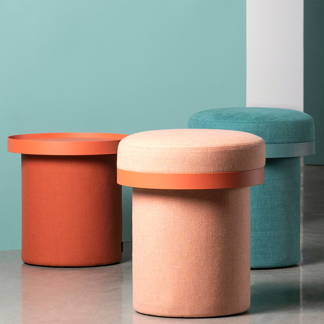 Stylish round stools in coral, peach, and teal with contrasting colored tops against a soft pastel backdrop.