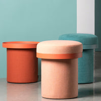 Stylish round stools in coral, peach, and teal with contrasting colored tops against a soft pastel backdrop.