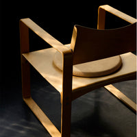 Light wood armchair featuring smooth curves and a natural finish against a dark background.