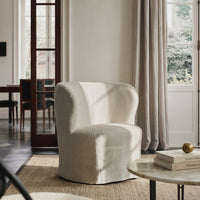 Soft white boucle armchair with a rounded silhouette, set against a neutral-toned room with natural light.