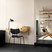 Modern black chair against light wooden desk, featuring minimalist design with soft beige and dark gray accents.