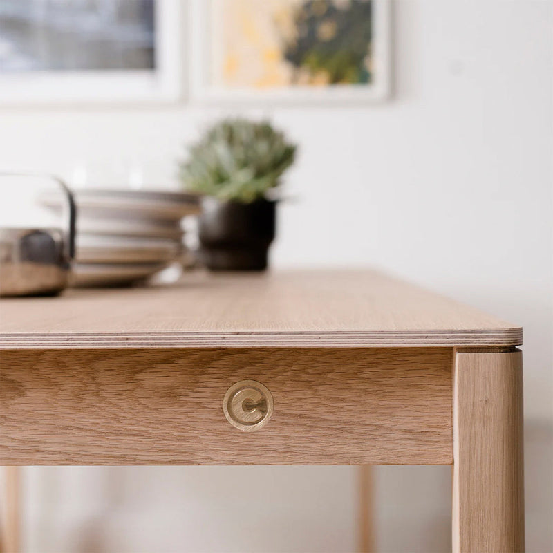 Light oak table with a smooth, natural finish and brass accent, showcasing a minimalist, modern design.