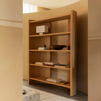 Curved wooden bookshelf in warm natural tones with a sleek and modern design, featuring multiple open shelves.