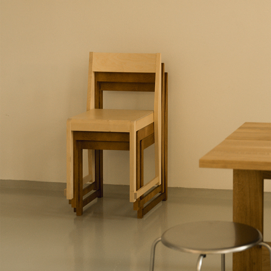 Minimalist wooden chair in light beige with dark wood accents, featuring a simple, modern design.