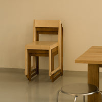 Minimalist wooden chair in light beige with dark wood accents, featuring a simple, modern design.