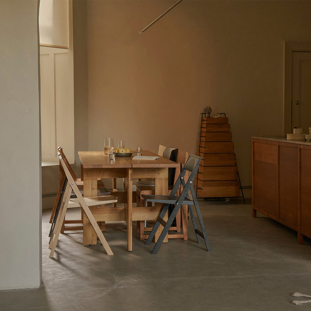Neutral-toned room featuring a wooden table, light and dark wood chairs, with a minimalist and warm color palette.