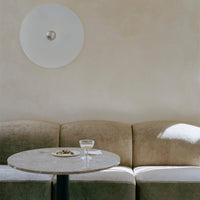 Beige velvet sofa with curved edges, light marble table, and soft wall textures complement the minimalist design.