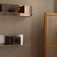 "Elegant beige wall with metallic shelves, featuring rustic clay and wooden decor elements."