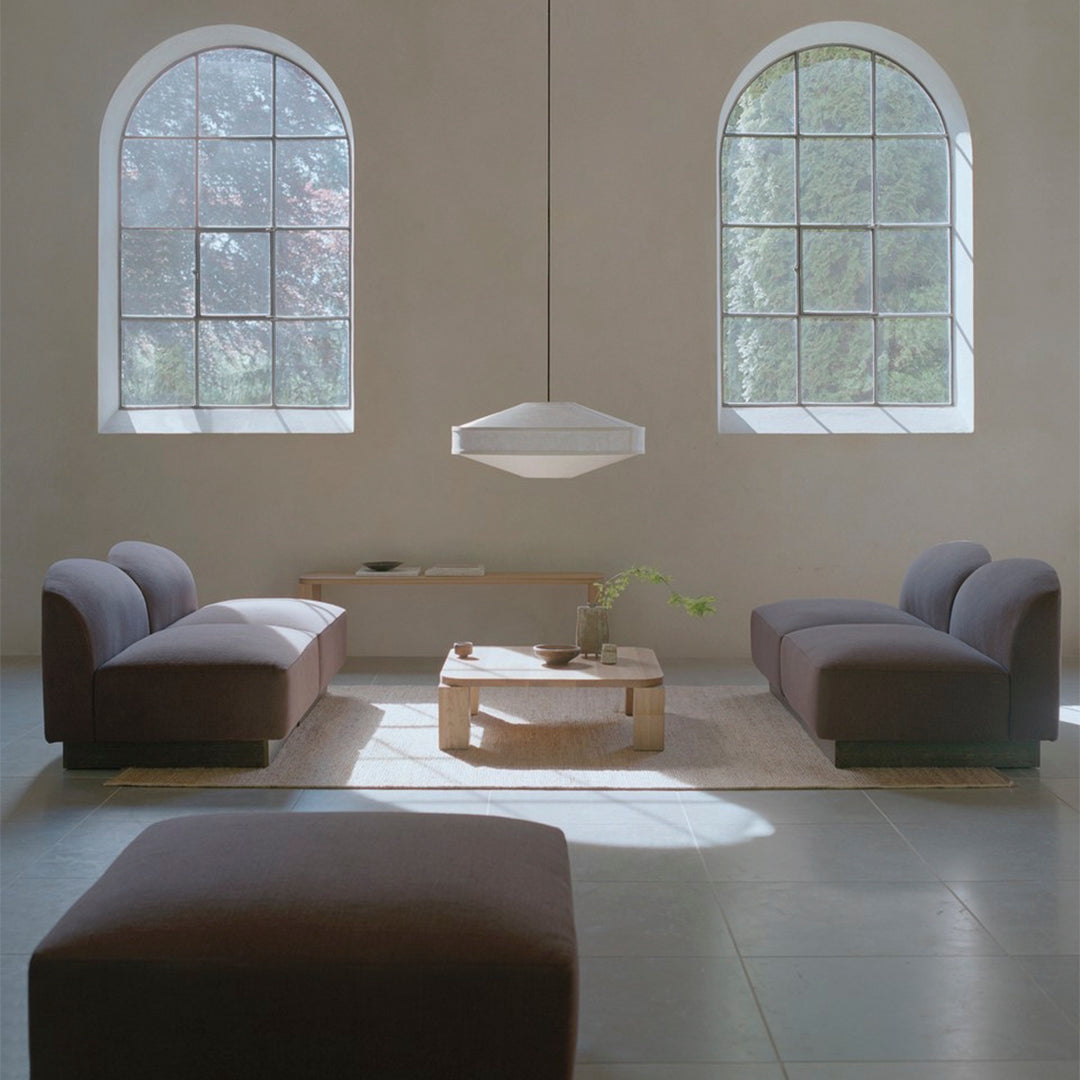 Modern living room featuring brown sofas, minimalist decor, soft gray flooring, and natural light from large windows.