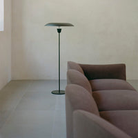 Soft mauve sofa paired with a sleek black floor lamp against a neutral backdrop. Minimalist design and subtle textures.