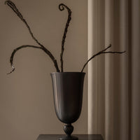 Elegant dark vase with textured surface, featuring slender, twisted branches against a neutral backdrop.