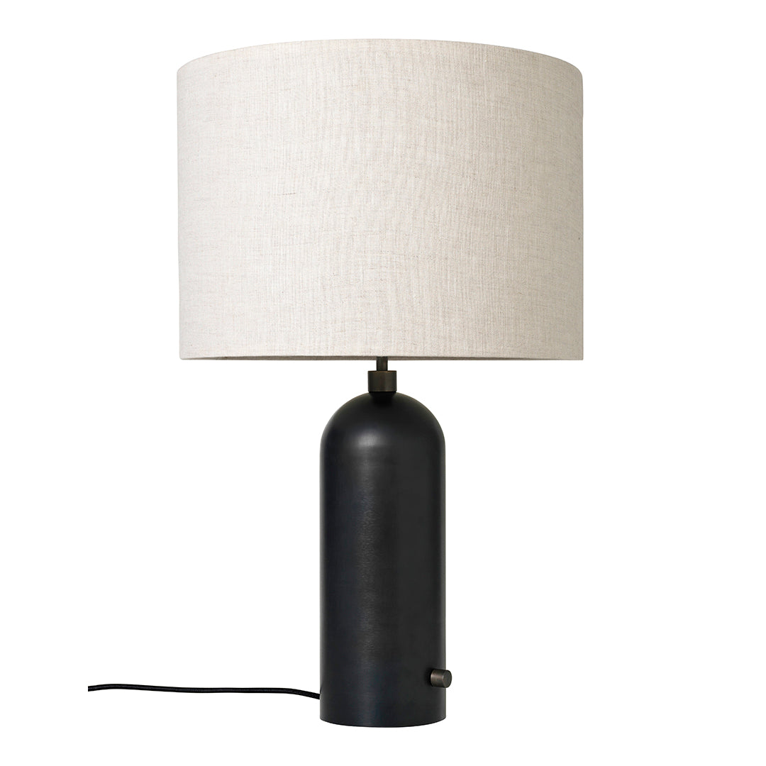 Black cylindrical lamp base with a textured cream fabric shade. Modern and minimalist design elements combined.