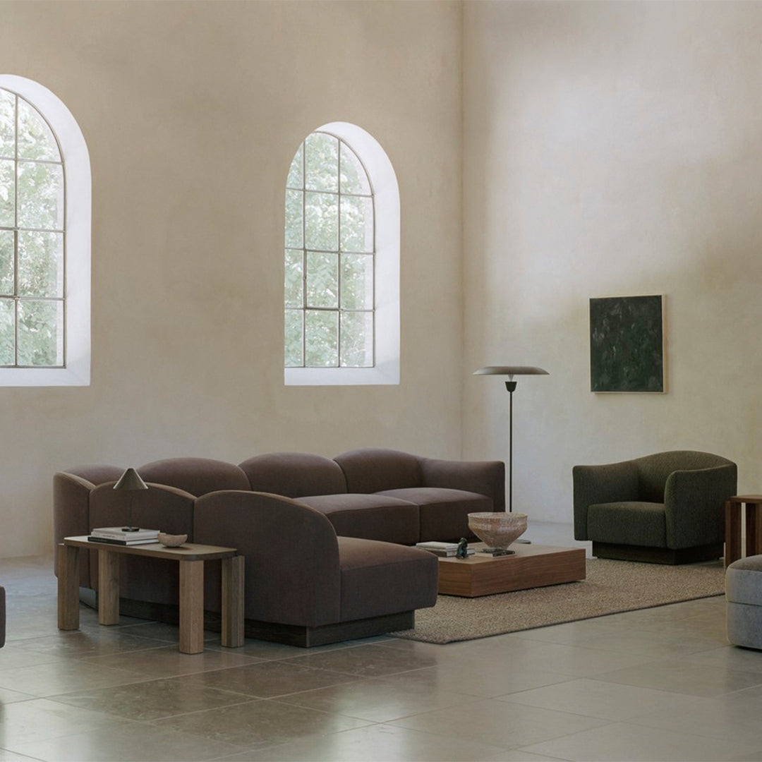 Modern living room with warm brown sofas, green accents, and soft neutral tones, creating a cozy aesthetic.