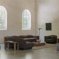 "Modern lounge with earthy brown and green sofas against a light beige background, featuring elegant curves."