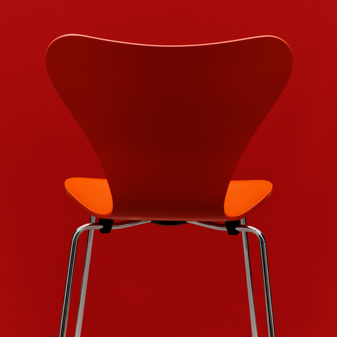 Red chair with an orange seat and sleek chrome legs, featuring a minimalist design. Perfect for modern decor.